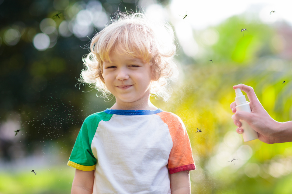 Mãe borrifando repelente infantil em seu filho para afastar mosquitos. Foto: Reprodução / Canva